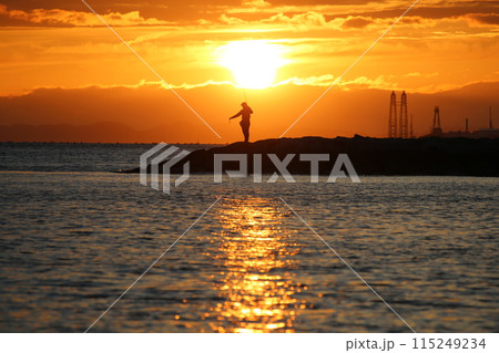 海に沈む夕日と釣りをする人 115249234