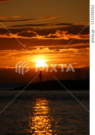 海に沈む夕日と釣りをする人 115249262