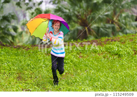 Child playing in rain. Kid jumping in puddle. Child playing in rain. Kid jumping in puddle. 115249509
