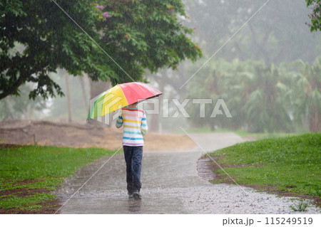 Child playing in rain. Kid jumping in puddle. 115249519