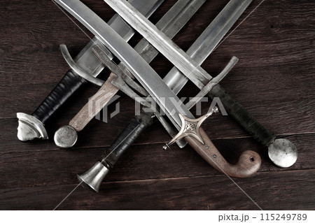 Swords and sabre on wooden background. Swords and sabre on wooden background. 115249789