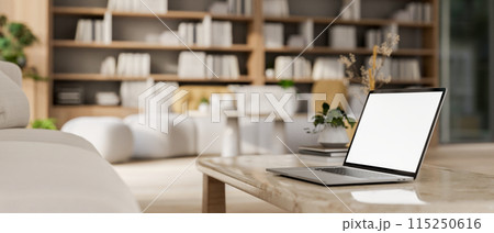 A laptop computer on a neutral marble coffee table in a contemporary, spacious living room. 115250616