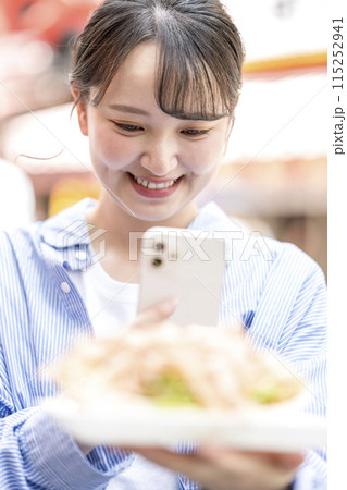 明るい屋外でたこ焼きをスマホで撮影する若くて可愛いSNS好きな女性|大阪府大阪市道頓堀商店街 明るい屋外でたこ焼きをスマホで撮影する若くて可愛いSNS好きな女性|大阪府大阪市道頓堀商店街 115252941