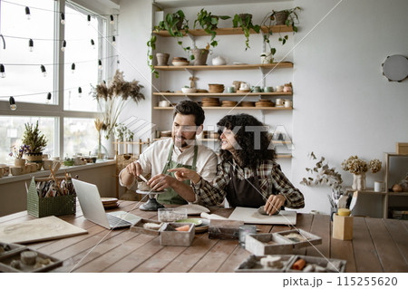 Mature man and woman sculpting clay while watching online video course 115255620