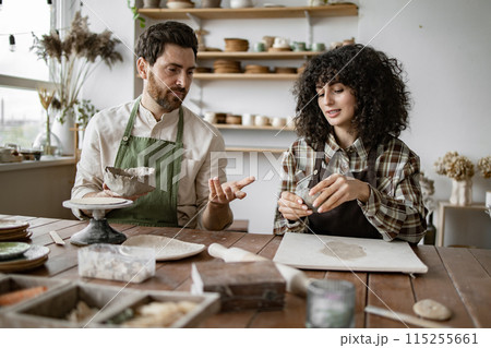 Bearded mature man and woman sculpting clay in pottery studio 115255661