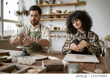 Mature man and woman sculpting clay in pottery studio Mature man and woman sculpting clay in pottery studio 115255665