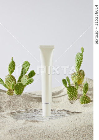 The photo of minimalist style on white texture, in front of is a cosmetic tube without label, some cactus decorated on both sides. Photo was shot from front angle, copy space 115256614