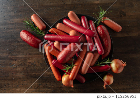 Various sausages with rosemary and onion on a old wooden table. 115256953