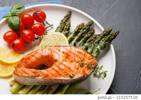 Grilled salmon steak over grilled asparagus, a delicious meal 115257510