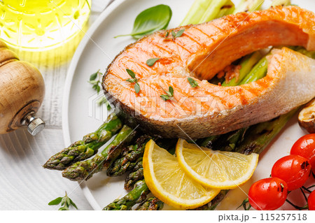 Grilled salmon steak over grilled asparagus, a delicious meal Grilled salmon steak over grilled asparagus, a delicious meal 115257518