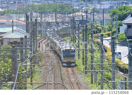 高台のフェンス越しに見るJR宇都宮線の通勤電車、E233系：埼玉県蓮田市 115258068