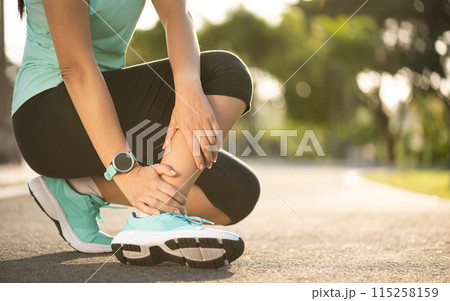 Ankle sprained. Young woman suffering from an ankle injury while exercising and running. Healthcare and sport concept. Ankle sprained. Young woman suffering from an ankle injury while exercising and running. Healthcare and sport concept. 115258159