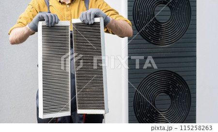 Worker in gloves holding two dirty air filters from a home ventilation system. Worker in gloves holding two dirty air filters from a home ventilation system. 115258263