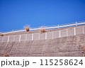 コンクリートの壁と青空と白いガードパイプ 115258624