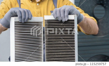 Worker holding two dirty air filters from a home ventilation system. Worker holding two dirty air filters from a home ventilation system. 115259757