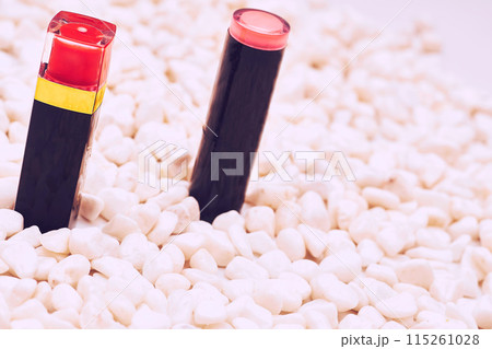 Two red pink lipsticks on pink pebbles stones 115261028