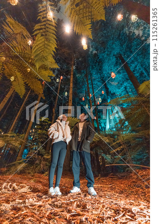 Asian couple tourist enjoying in Redwood or Whakarewarewa forest with illuminated lighting and lamp at New Zealand 115261365