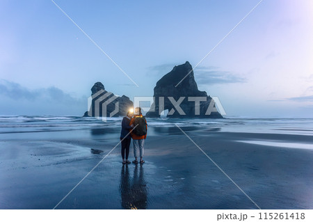 Asian couple enjoying on Wharariki beach with iconic rocky mountain in archway island at New Zealand Asian couple enjoying on Wharariki beach with iconic rocky mountain in archway island at New Zealand 115261418