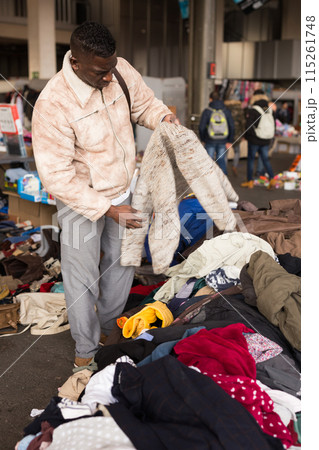 South African guy selects second-hand clothes at a flea market 115261748