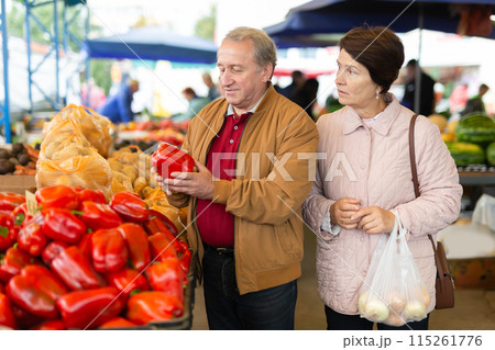 Elderly men and women buying peppers at an open market Elderly men and women buying peppers at an open market 115261776