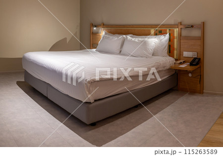 Cozy hotel bedroom with comfortable bed, lamp, and pillows, modern hotel room interior 115263589