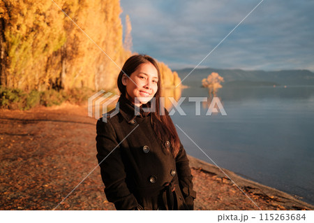 Beautiful asian woman enjoying with sunlight shines on yellow autumn trees at Wanaka Lake, New Zealand Beautiful asian woman enjoying with sunlight shines on yellow autumn trees at Wanaka Lake, New Zealand 115263684