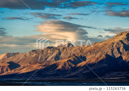 Sunrise over rocky mountain range on dry field in autumn 115263736