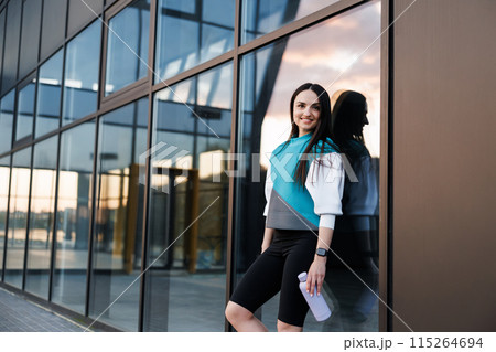 Woman holding bottle with water after morning workout. Young athletic woman standing near dark wall background after jogging Healthy lifestyle concept Woman holding bottle with water after morning workout. Young athletic woman standing near dark wall background after jogging Healthy lifestyle concept 115264694