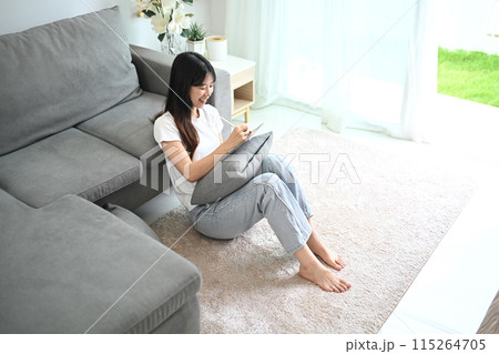 Smiling young woman freelancer in casual clothes using digital tablet at home Smiling young woman freelancer in casual clothes using digital tablet at home 115264705