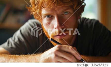 Thoughtful man with a pen and intense gaze. 115265165