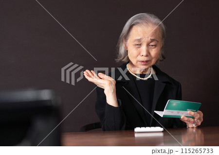 喪服で通帳を見るシニア女性　孤独　 115265733