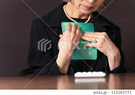 喪服で通帳を見るシニア女性　孤独　手元 115265771