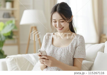 リビングでスマートフォンを使う若い女性 115267116