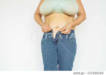 woman in jeans and top shows fat belly, saggy skin, excess weight woman in jeans and top shows fat belly, saggy skin, excess weight 115268168