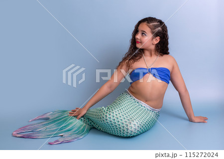 Pretty girl in a mermaid costume, isolated on a blue background, looking away 115272024
