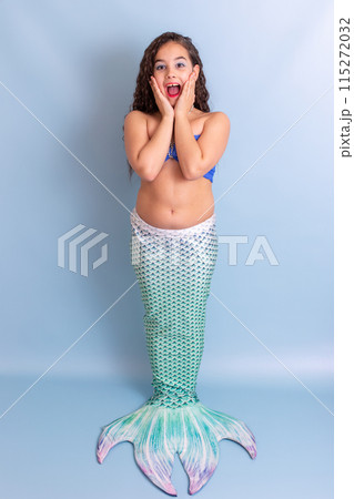 Pretty happy surprised girl in mermaid costume stand on blue background Pretty happy surprised girl in mermaid costume stand on blue background 115272032