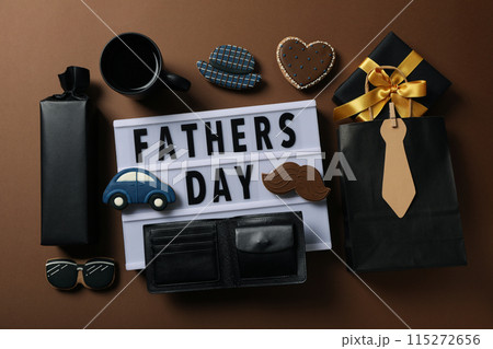 Inscription on a white chalkboard father's day, on a brown background, with gifts. 115272656