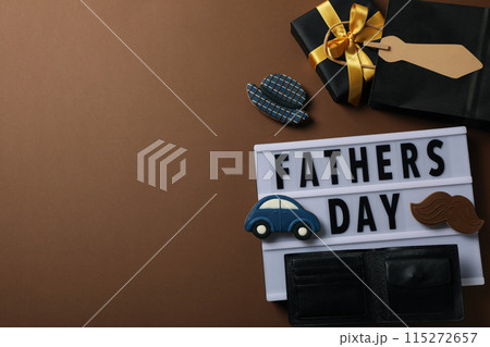 Inscription on a white chalkboard father's day, on a brown background, with gifts. 115272657