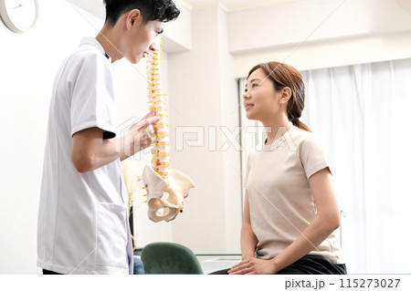 骨の模型を使い女性患者に説明する男性医師 骨の模型を使い女性患者に説明する男性医師 115273027