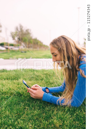Fitness woman using mobilephone while exercising. Smiling woman doing stretching workout  115274343