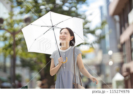 街中を日傘をさして歩く若い女性 115274976