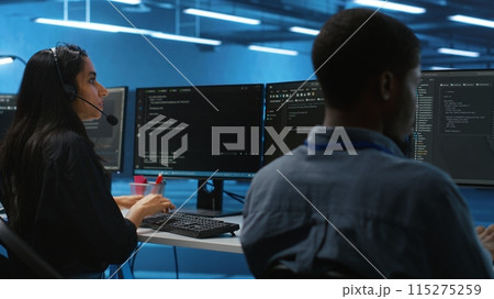 Woman talking in headphone mic, doing system analysis of server farm supercomputers. IT support worker in remote call using headset microphone in data center housing storage infrastructure 115275259