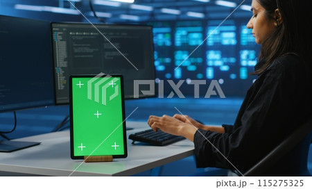 Focus on isolated screen tablet next to admin programming in server room providing computing resources for workloads. Chroma key device on desk used by worker supervising data center supercomputers 115275325