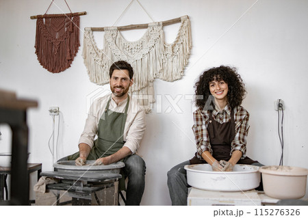 Man and woman potters working on clay vase in studio 115276326