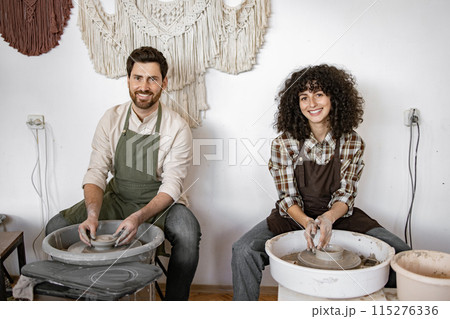 Man and woman potters working with clay on pottery wheels Man and woman potters working with clay on pottery wheels 115276336