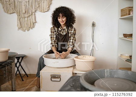 Female potter working with clay on a pottery wheel in a studio 115276392