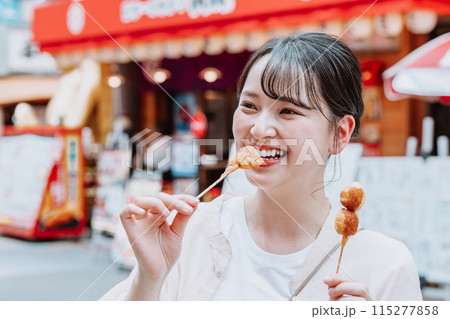 大阪 新世界で名物の串カツを食べる若い女性 大阪 新世界で名物の串カツを食べる若い女性 115277858