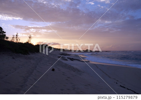 Waves break and crash towards the Hanakailio Beach with dramatic blue-pink cloudy skyline at dusk 115279879