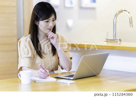 ダイニングテーブルで勉強する女性 115284360