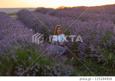 A woman sits in a field of purple flowers 115284926
